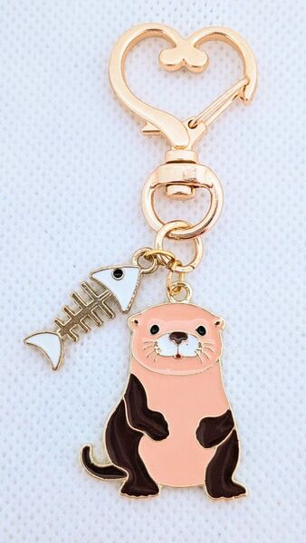 白色の魚の骨とちょこんと座ったモカピンクのカワウソキーホルダー