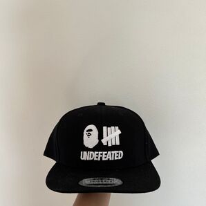 ブラックのスナップバックキャップ刺繍ロゴ付きエイプ- ブランド:UNDEFEATED×APE- デザイン: スナップバックキャップ