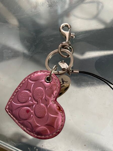 ピンクのレザー製ハート型キーホルダー、COACHのロゴ入り。