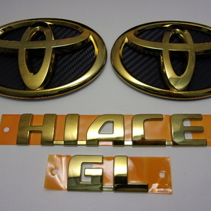 7トレジャ-【新品トヨタ純正エンブレムを加工】 200系 ハイエース ワイドボディー GL プレミアム ゴールド 4点(カーボン柄背景シート付)