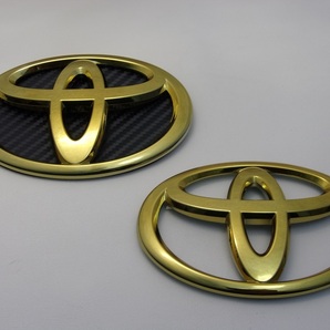 7トレジャー 【 トヨタ 90系 ヴォクシー VOXY 】 プレミアム ゴールド エンブレム F&R 2点(フロント:ブラックカーボン柄背景シート付き)