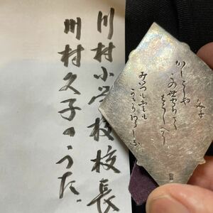 川村小学校　校長　川村久子先生のうたです。大きさは7x5x0、4cm程、銅製で裏には銀の板が貼ってあり，そこに和歌が彫ってあります。